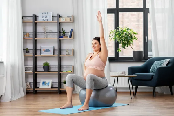 Mujer embarazada haciendo ejercicio en la pelota de fitness en casa — Foto de Stock