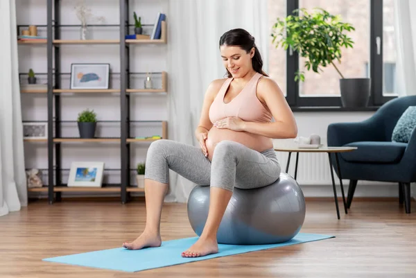 Mujer embarazada haciendo ejercicio en la pelota de fitness en casa —  Fotos de Stock