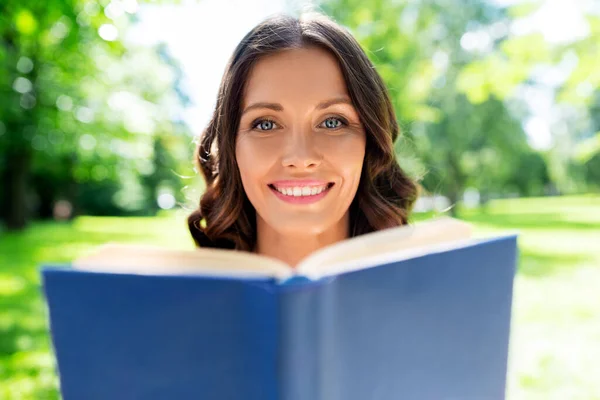 Счастливая улыбающаяся женщина читает книгу в летнем парке — стоковое фото