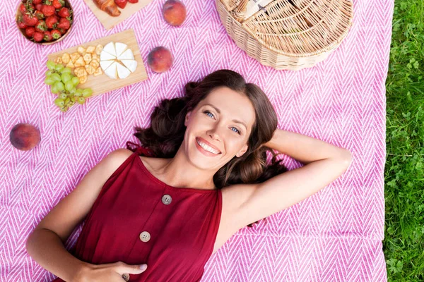 Gelukkig vrouw liggend op picknick deken in zomer park — Stockfoto