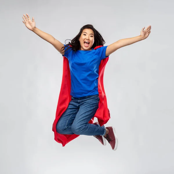 Lycklig asiatisk kvinna i röd superhjälte cape hoppa — Stockfoto