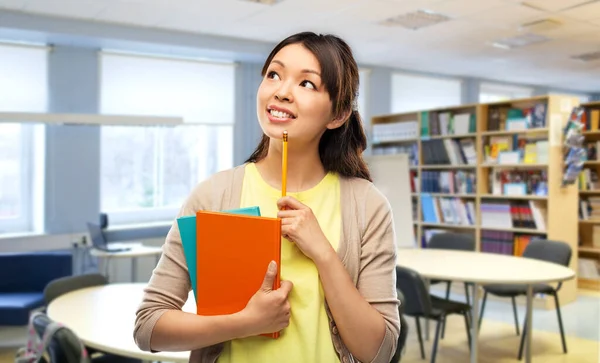 Aziatische student vrouw met boeken in bibliotheek — Stockfoto