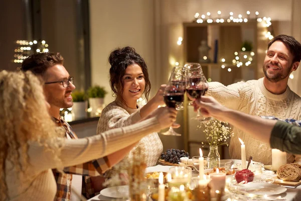 Amigos felices bebiendo vino tinto en la fiesta de Navidad —  Fotos de Stock