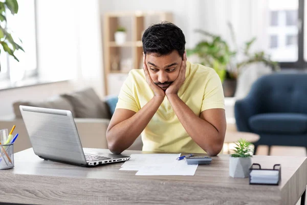 Man met rekenmachine en papieren die thuis werken — Stockfoto