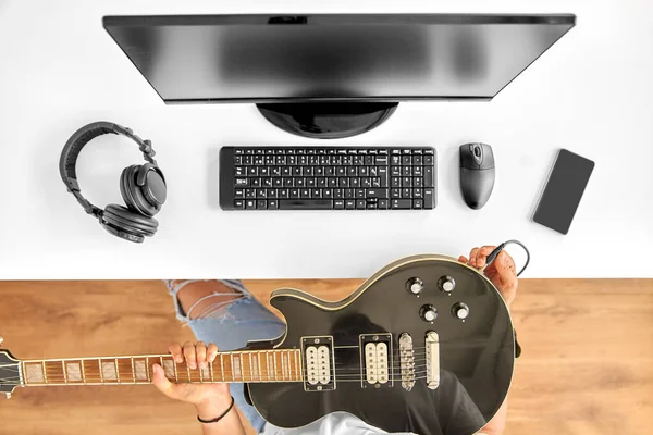 Jeune homme avec guitare tuning informatique à table — Photo