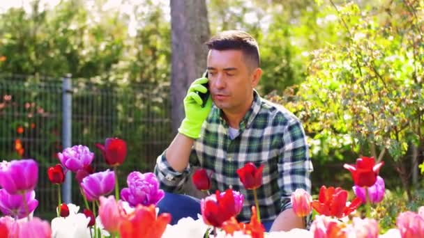 Мужчина среднего возраста со смартфоном в цветочном саду — стоковое видео
