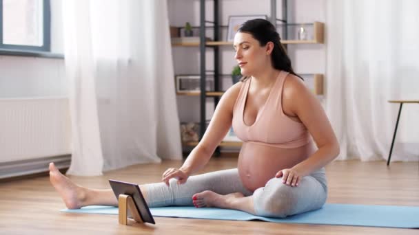 Pregnant woman with tablet pc doing sports at home — Stock Video