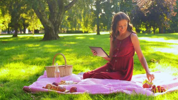 Mujer feliz con la tableta en el picnic en el parque — Vídeo de stock