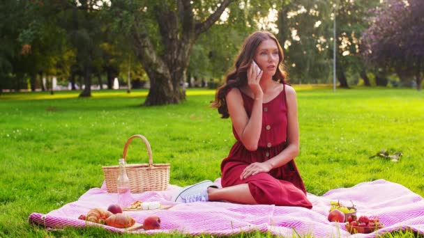 Mulher chamando no smartphone em piquenique no parque — Vídeo de Stock