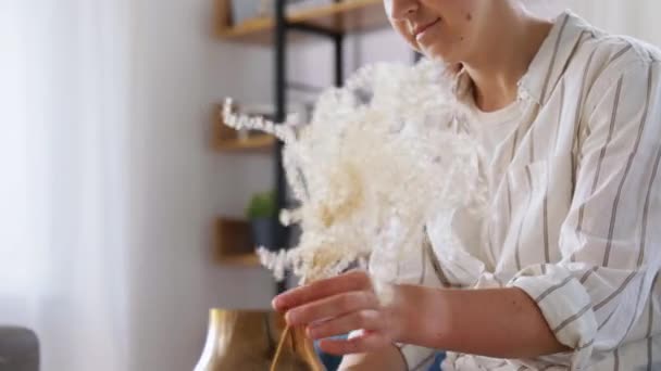 Жінка влаштовує сухі квіти у вазі вдома — стокове відео