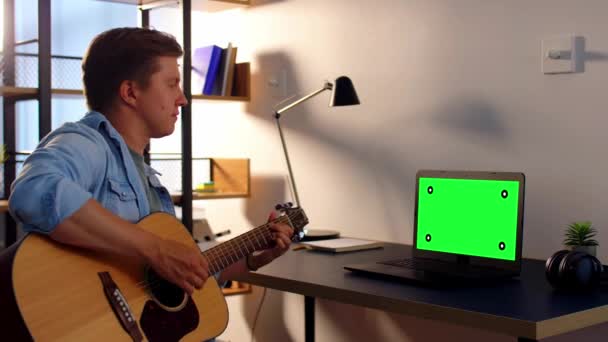 Jeune homme avec ordinateur portable jouant de la guitare à la maison — Video