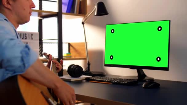 Jeune homme avec ordinateur jouant de la guitare à la maison — Video