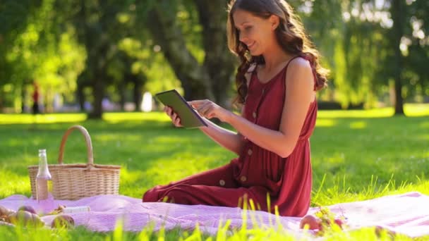 Mulher feliz com computador tablet em piquenique no parque — Vídeo de Stock