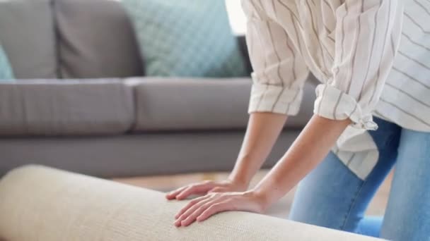 Jonge vrouw ontvouwt tapijt thuis — Stockvideo