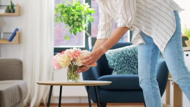 Woman placing flowers on coffee table at home — Stock Video