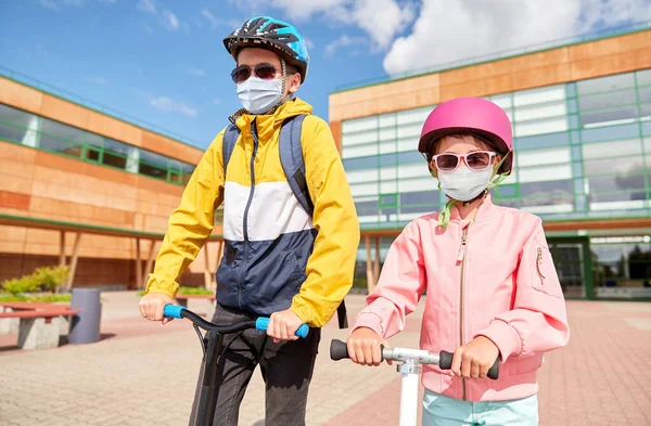 Dzieci w maskach jazda na skuterach nad szkołą — Zdjęcie stockowe