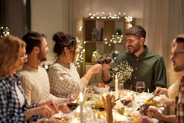 Glada vänner dricker rött vin på julfesten — Stockfoto