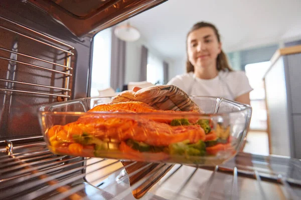 Mujer cocina comida en el horno en casa cocina —  Fotos de Stock