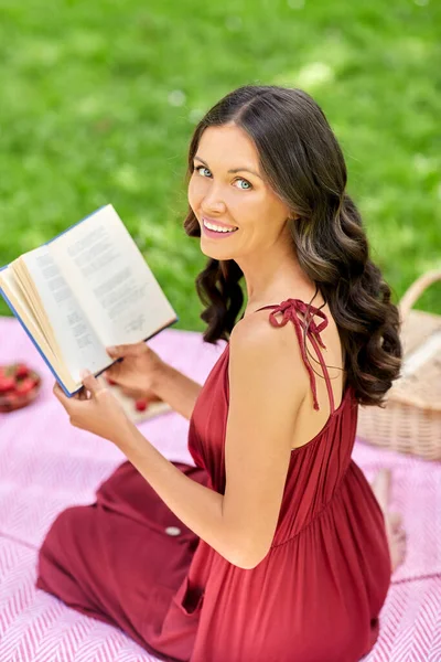 Ευτυχισμένη γυναίκα ανάγνωση βιβλίο στο πικνίκ στο πάρκο το καλοκαίρι — Φωτογραφία Αρχείου