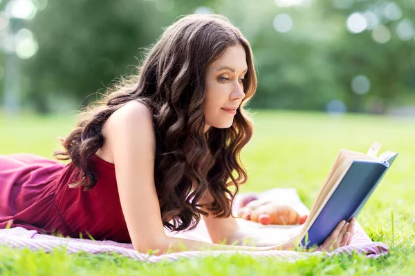 Ευτυχισμένη νεαρή γυναίκα διαβάζει βιβλίο στο πάρκο το καλοκαίρι — Φωτογραφία Αρχείου