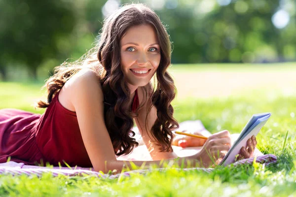 Šťastná žena s deníkem nebo notebookem v parku — Stock fotografie