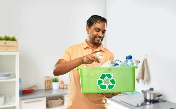 Sonriente joven indio hombre clasificación de residuos de plástico — Foto de Stock