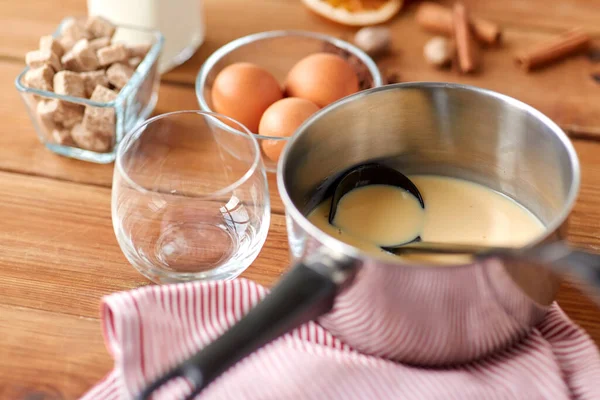 Hrnec s vaječným koňakem, ingrediencemi a kořením na dřevě — Stock fotografie