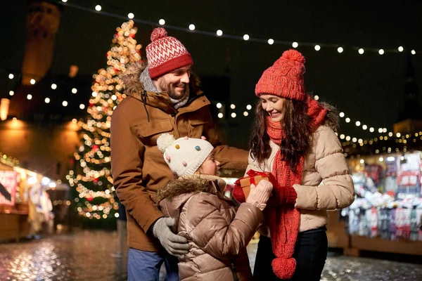Happy family with gift at christmas market in city — Stock Photo, Image