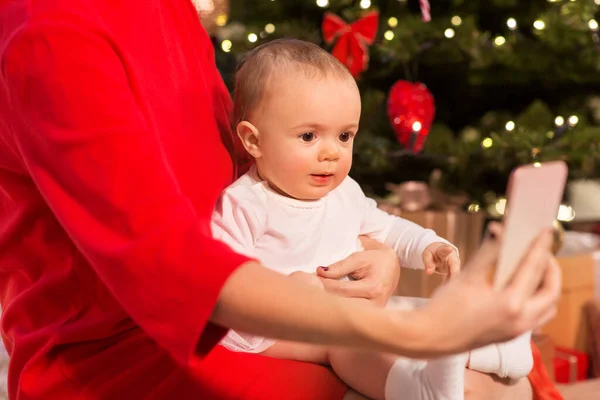 Mãe com bebê menina e smartphone no Natal — Fotografia de Stock