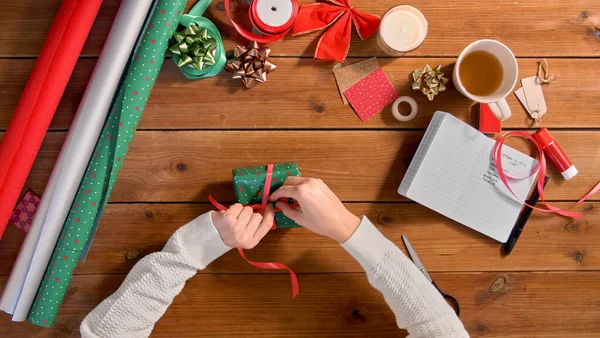 Руки упаковки рождественский подарок и завязывания ленты — стоковое фото