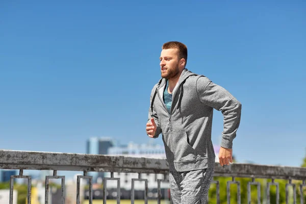 Happy young man running across city bridge — Stock Photo, Image
