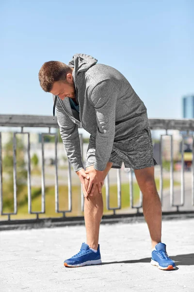 Ung man med skadat knä eller ben utomhus — Stockfoto