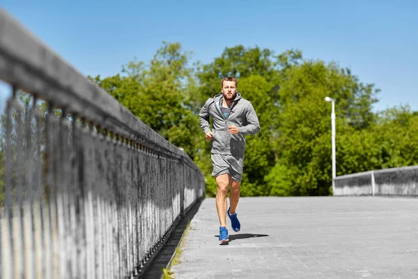 Heureux jeune homme courir à travers le pont de la ville — Photo