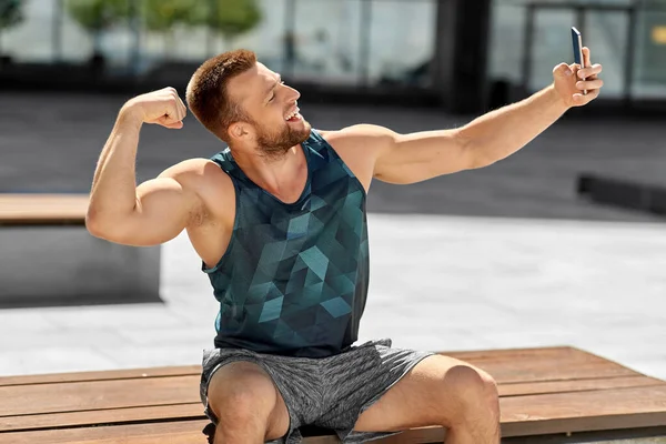 Muž užívající selfie s telefonem a ukazující biceps — Stock fotografie