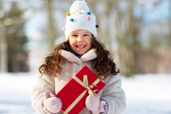 Happy girl with red christmas gift in winter park — Stock Photo, Image