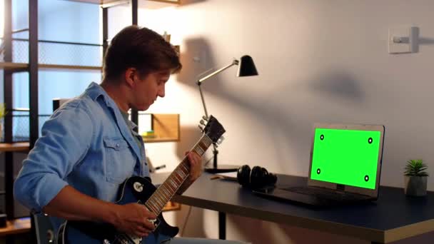 Jeune homme avec ordinateur portable jouant de la guitare à la maison — Video