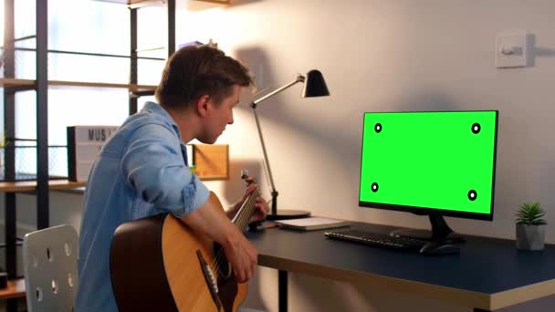 Jeune homme avec ordinateur jouant de la guitare à la maison — Video