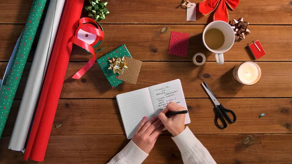 Manos escribiendo para hacer la lista en el cuaderno de Navidad —  Fotos de Stock