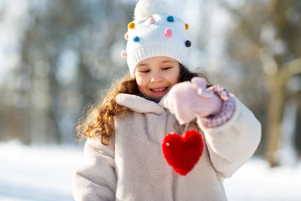 Gelukkig klein meisje met hart buiten in de winter — Stockfoto