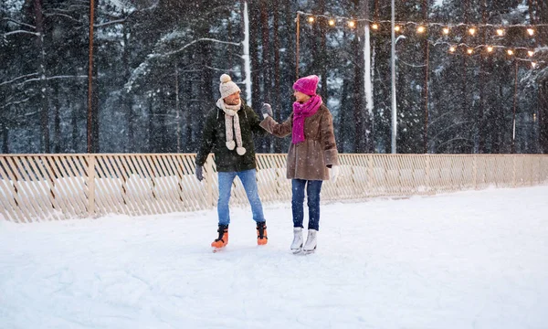 Happy couple holding hands on skating rink — Stock Photo, Image