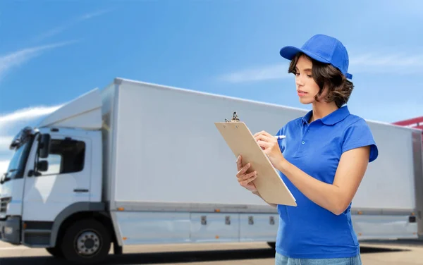 Delivery girl with clipboard and pen writing — Stock Photo, Image