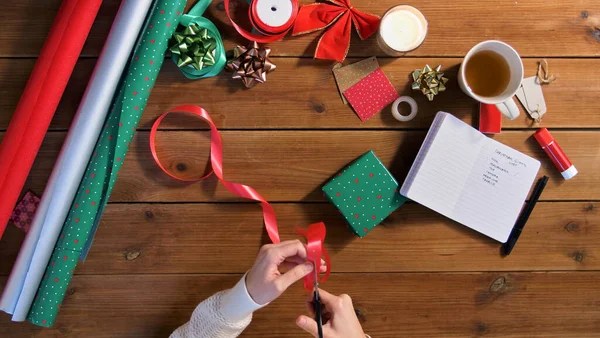 Mãos embalagem presente de Natal e fita de corte — Fotografia de Stock