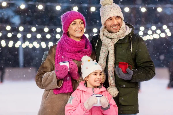 Familia feliz beber té caliente en pista de patinaje — Foto de Stock