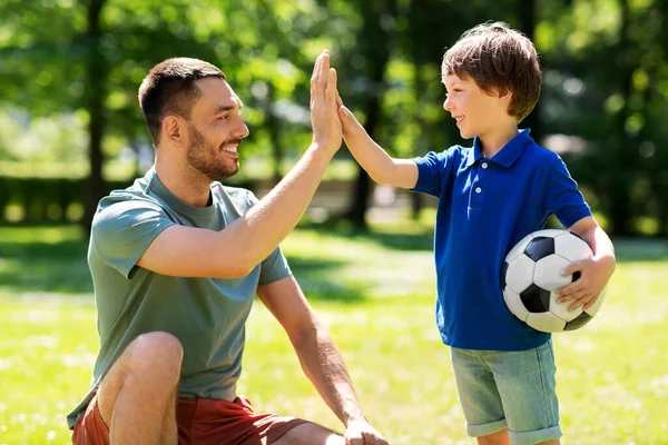 Otec dává pět na syna s fotbalovým míčem v parku — Stock fotografie