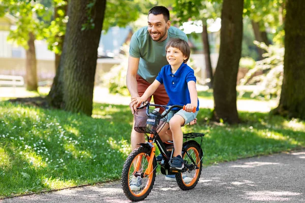 Vader leert kleine zoon fietsen in het park — Stockfoto