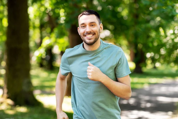 Happy young man running at summer park — Stock Photo, Image