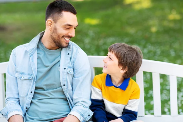 Far med son sitter på parkbänk och pratar — Stockfoto