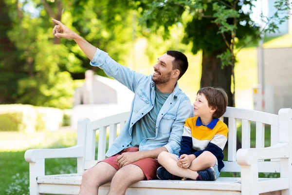 Padre mostrando algo a hijo sentado en el banco — Foto de Stock