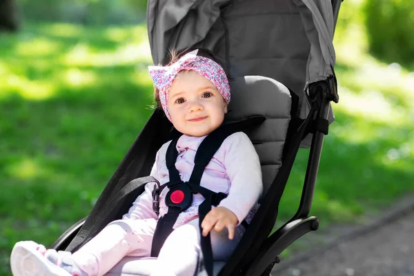Happy baby girl sitting in stroller at summer park — Stock Photo, Image