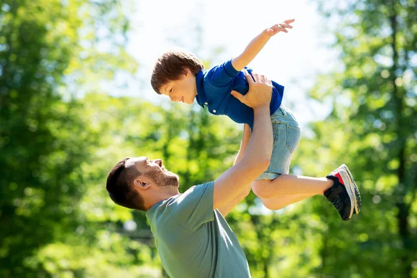 Szczęśliwy ojciec z synem bawiący się w letnim parku Obrazek Stockowy